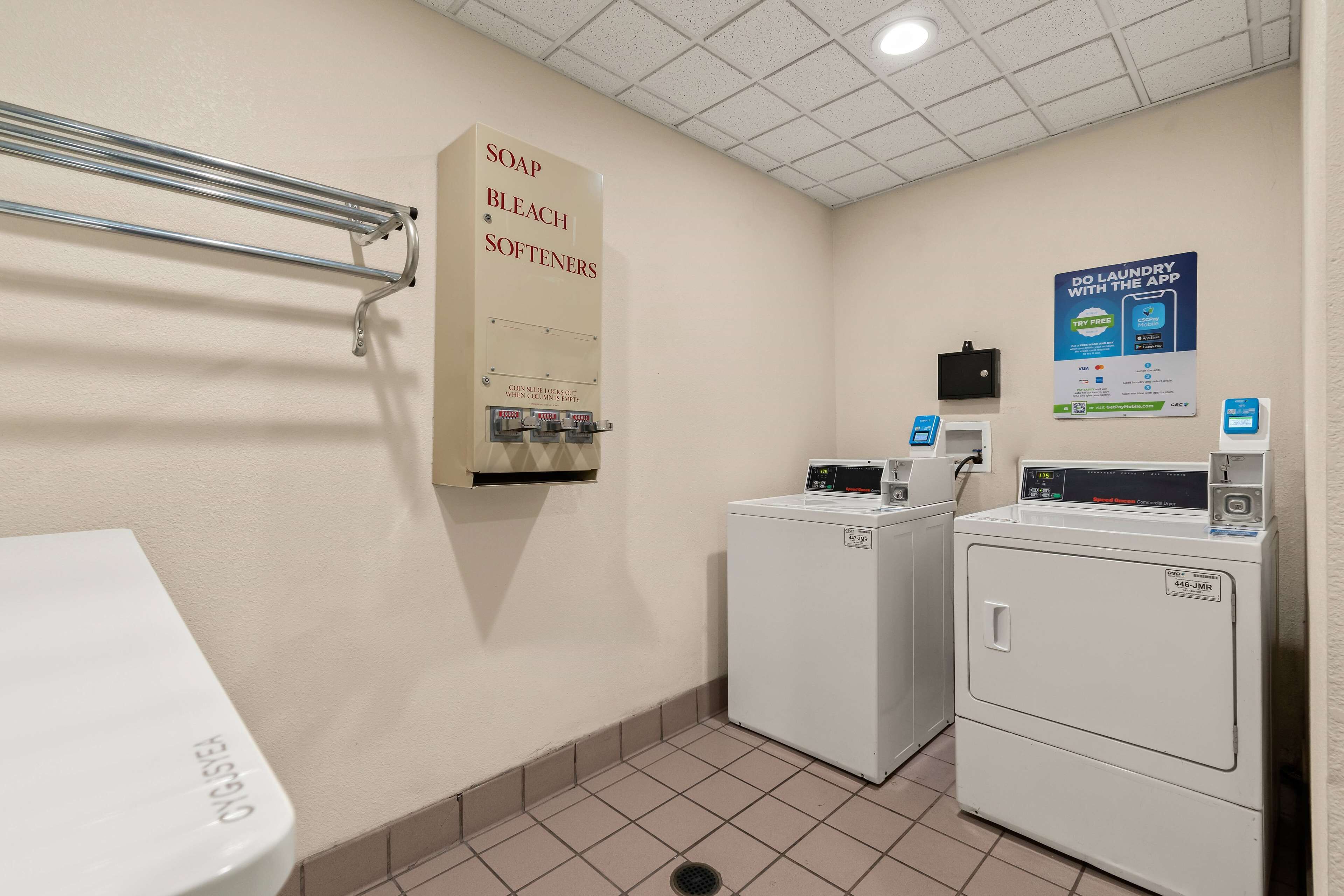 A laundry room with a soap and bleach dispenser, a washing machine, and a dryer.