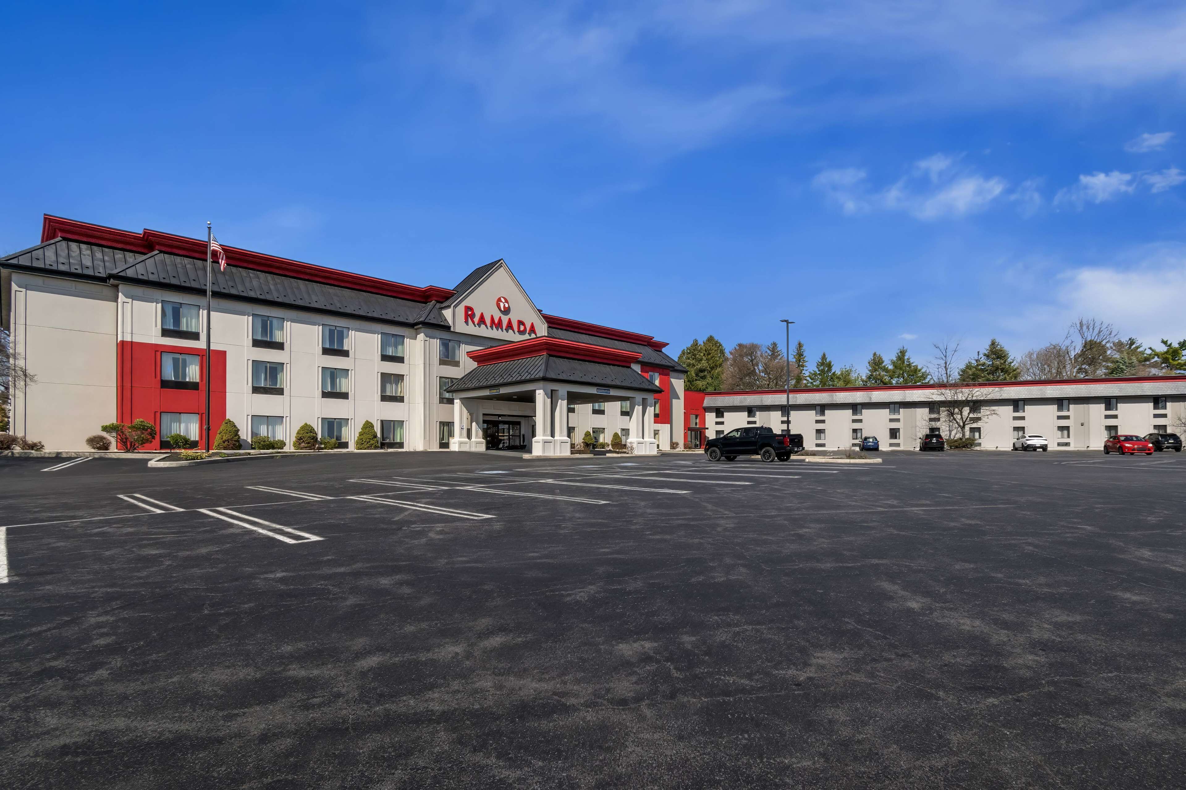 A Ramada hotel with a parking lot and several cars.