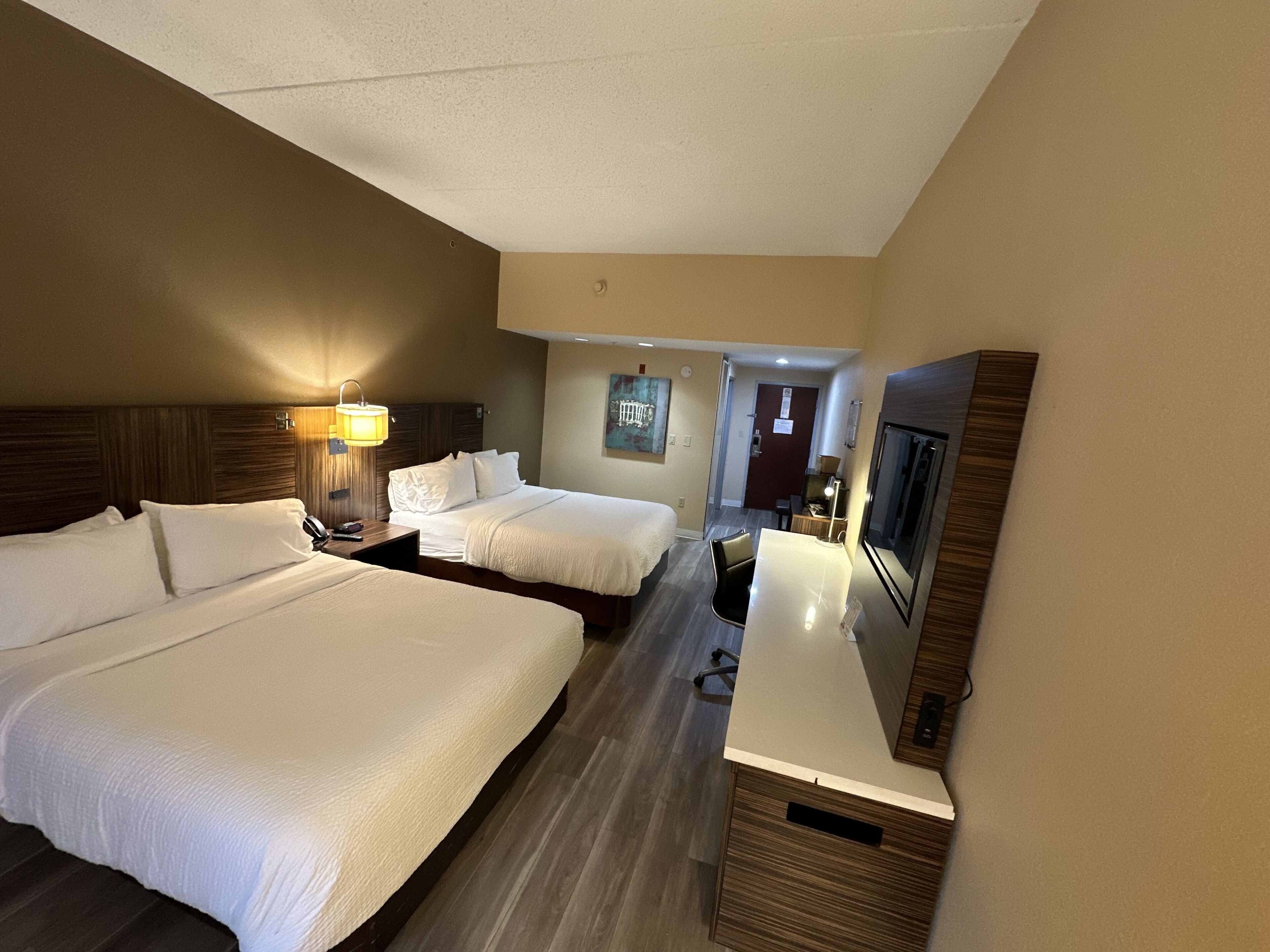 Een hotelkamer met twee bedden, een bureau, een televisie en een badkamer op de achtergrond.
