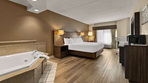 Ein Hotelzimmer mit einem großen Bett, einem separaten Badezimmer mit Badewanne, einem Schreibtisch und einem Fernseher.