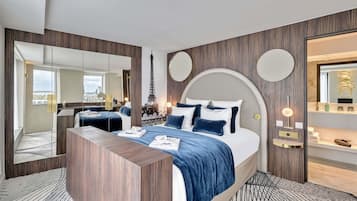 Quarto de hotel moderno com uma cama grande, uma mesa consola de madeira, um espelho e vista para a Torre Eiffel.
