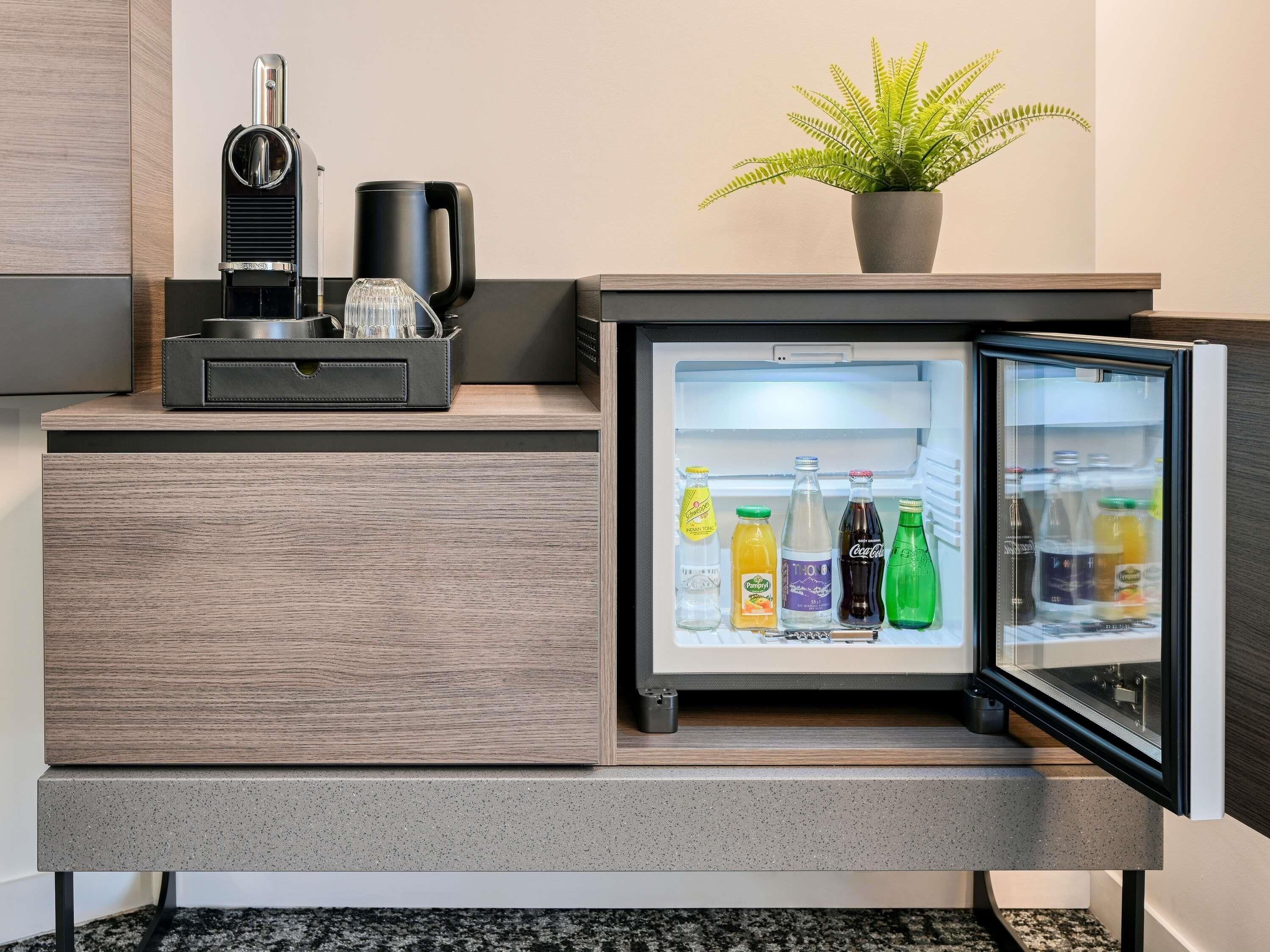 A modern kitchen with a built-in refrigerator, a coffee machine, and a potted plant.