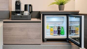 A modern kitchen with a built-in refrigerator, a coffee machine, and a potted plant.