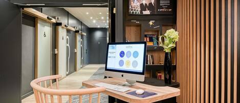 A modern hotel reception desk with a computer, a chair, and a wooden panel wall.