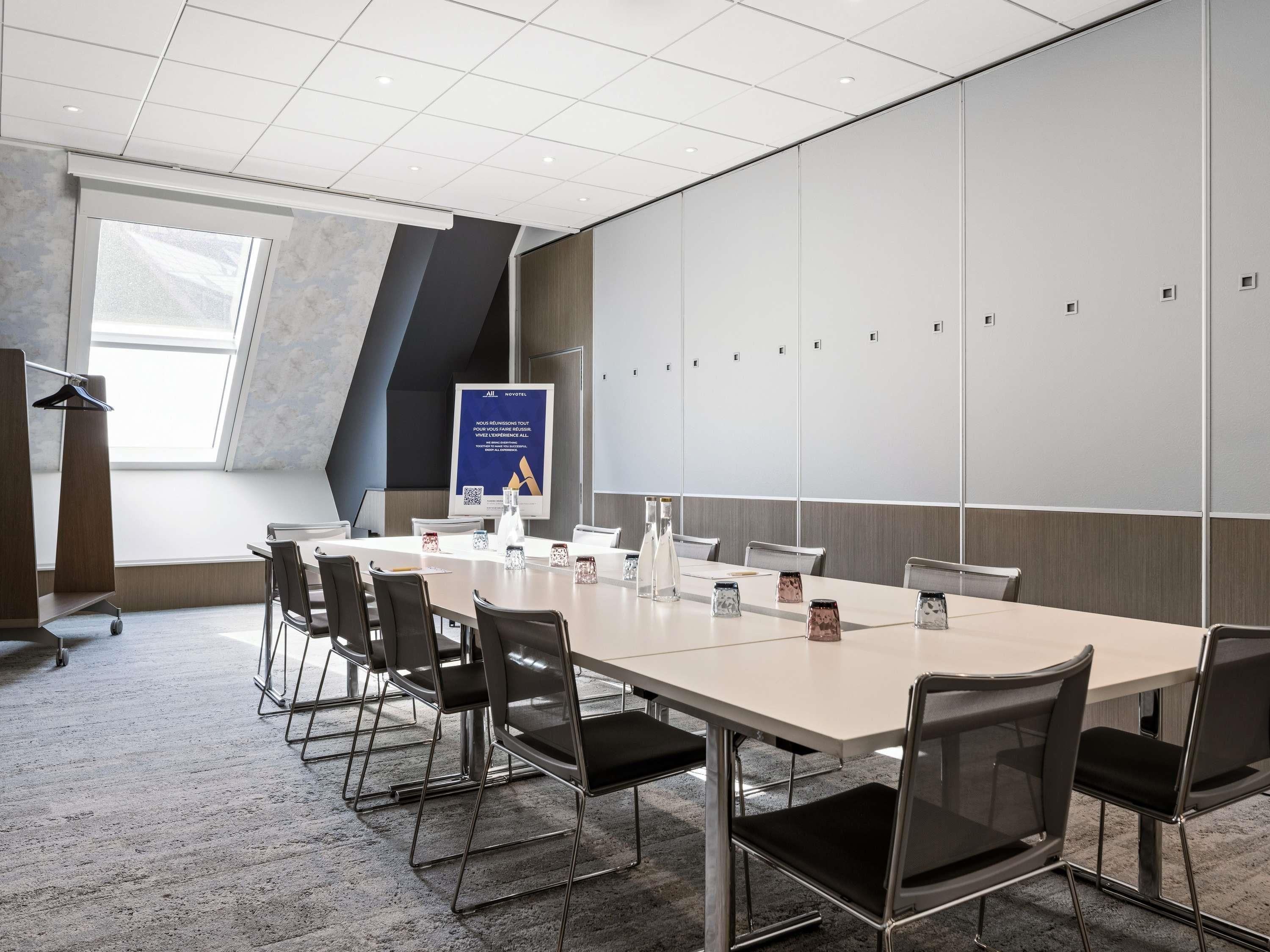 A conference room with a long table, chairs, a podium, and a poster on the wall.