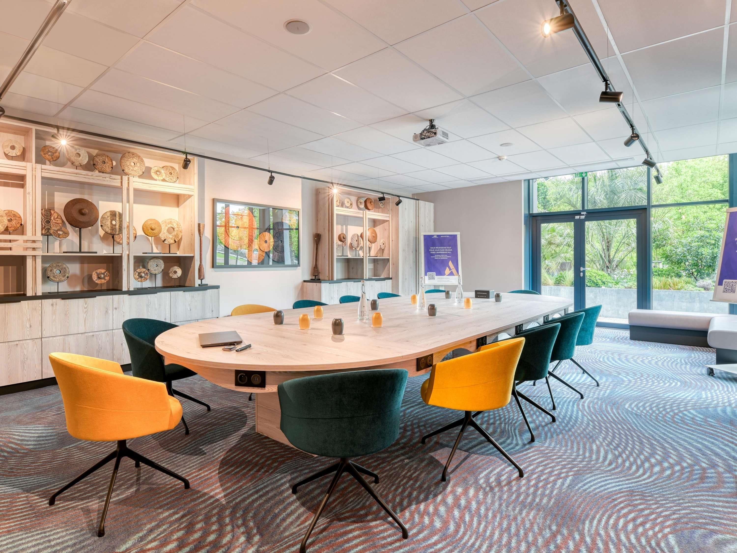 A conference room with a round table, chairs, a projector, and decorative items on shelves.