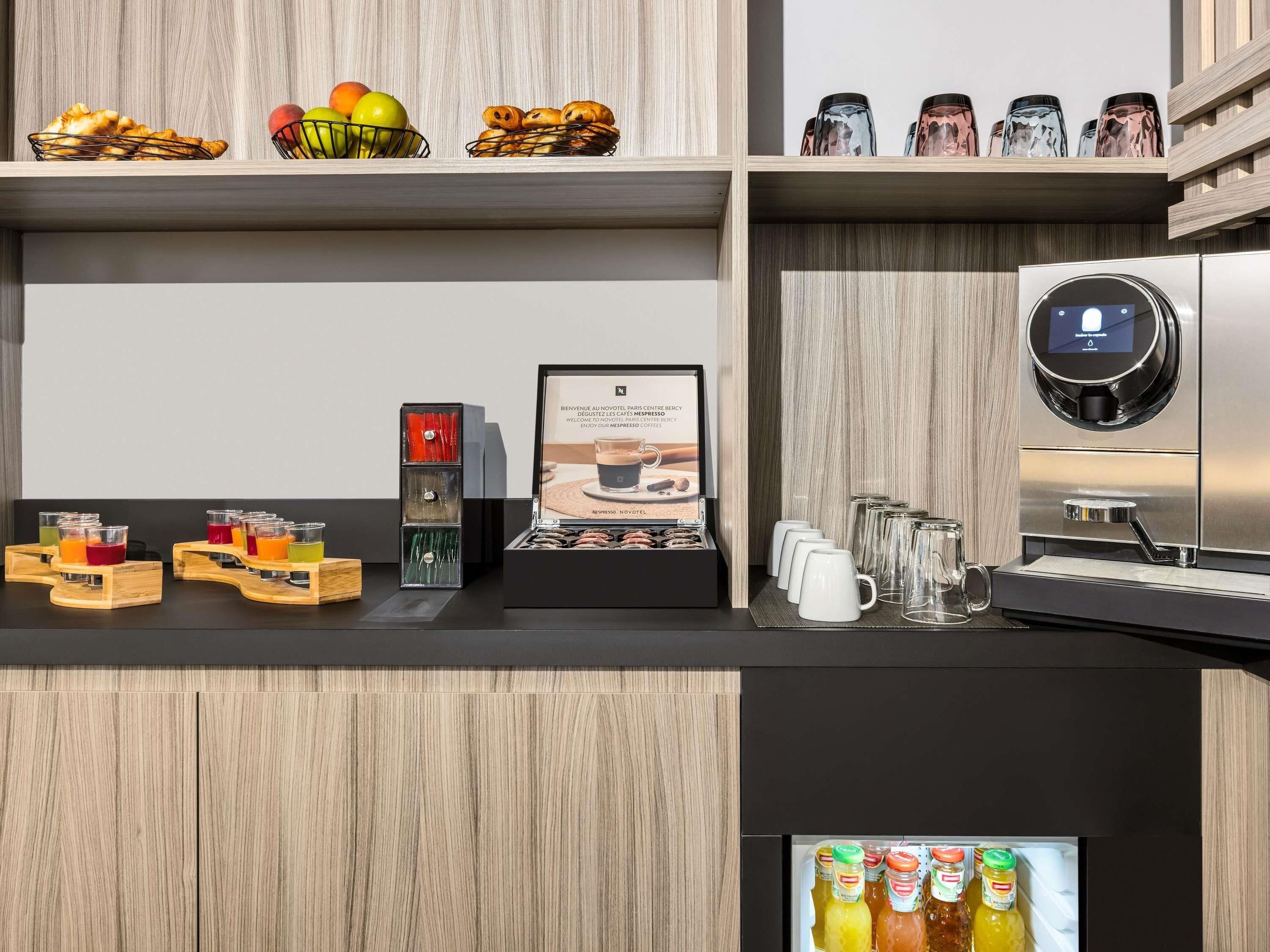 Un espace café moderne comprenant une machine à café, un présentoir de tasses à café et un assortiment de boissons dans des récipients en verre.