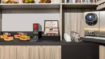 Un espace café moderne comprenant une machine à café, un présentoir de tasses à café et un assortiment de boissons dans des récipients en verre.