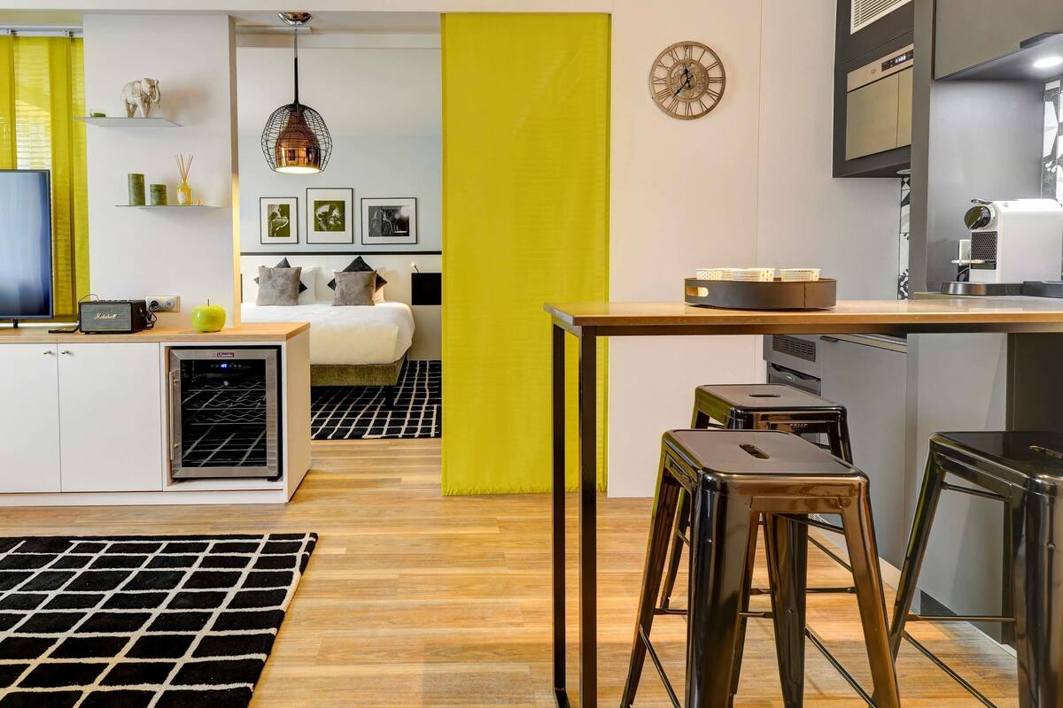 A modern kitchen with a dining area, a refrigerator, a microwave, and a coffee machine.