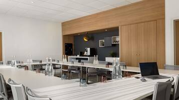 A modern conference room with a long table, multiple chairs, and a laptop on the table.