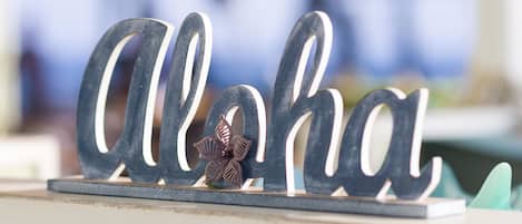 A decorative sign with the word "Aloha" in a stylized font, accompanied by a small flower decoration.
