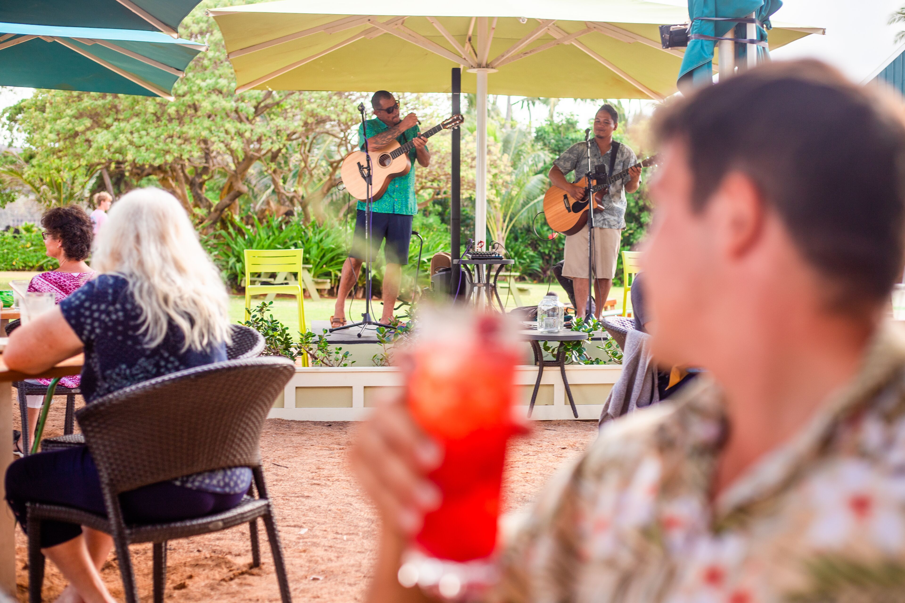 An outdoor patio area with a stage for live music, seating arrangements, and a casual dining setup.