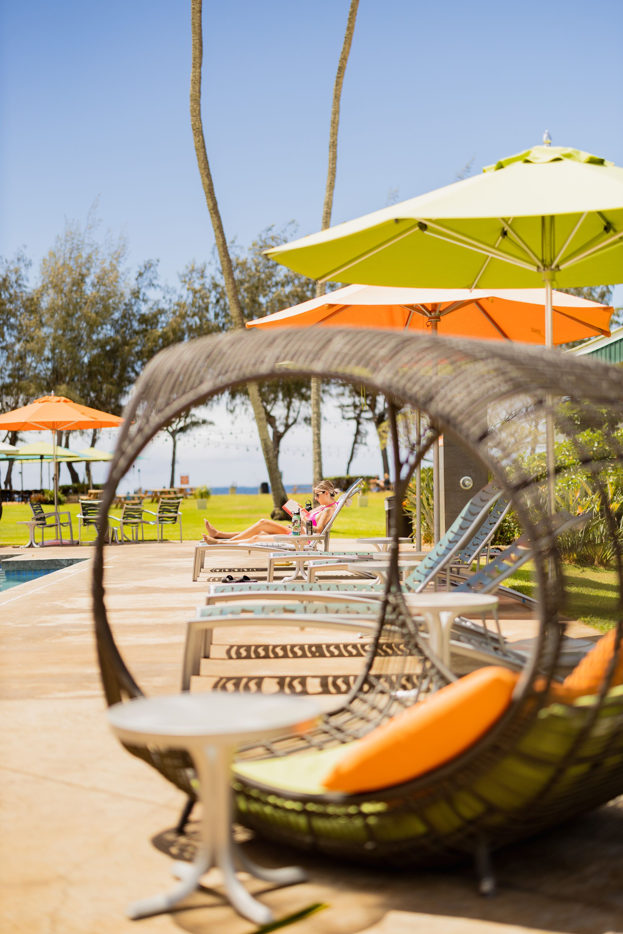 Un área junto a la piscina con sillones de descanso y sombrillas.