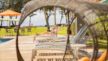 Un área junto a la piscina con sillones de descanso y sombrillas.
