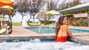 Un espace piscine doté d’un jacuzzi, de chaises longues et de parasols.