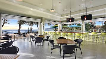 Un restaurante con terraza, bar y vista al océano.