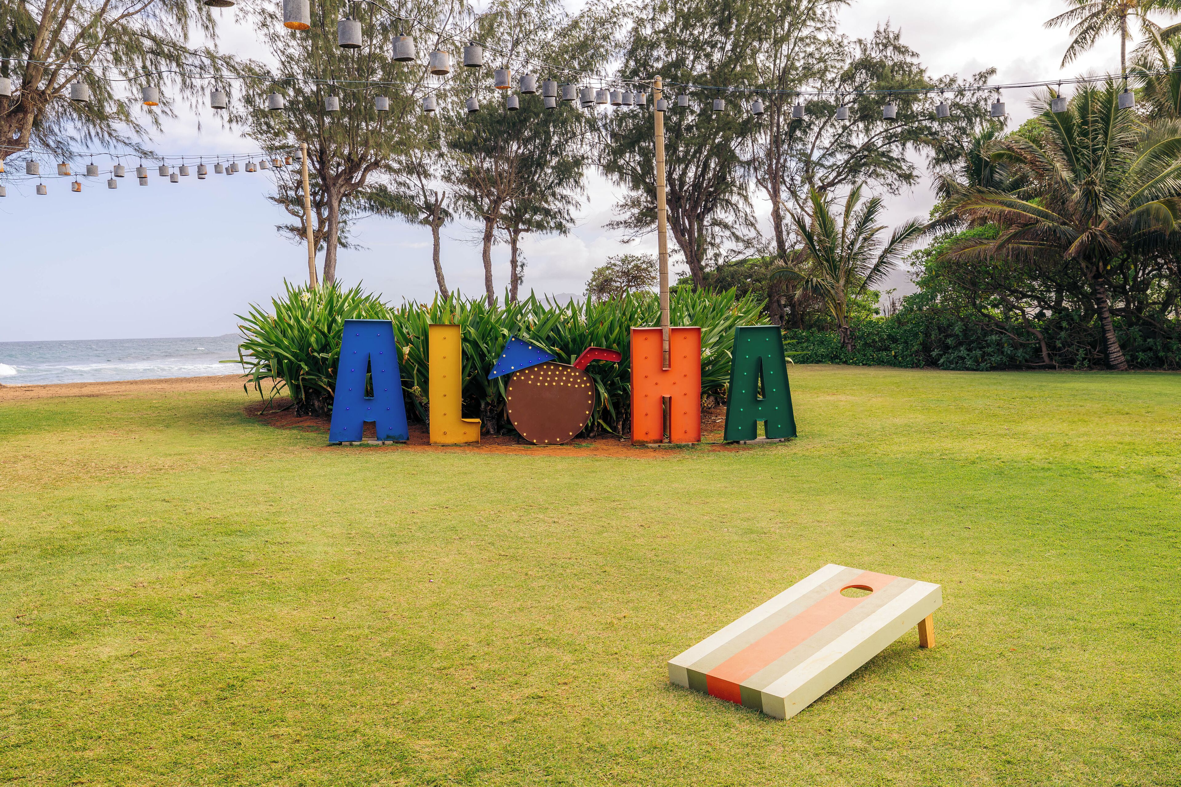 Un espacio cubierto de césped con jardineras de formas de letras de colores y una mesa para el juego de shuffleboard.