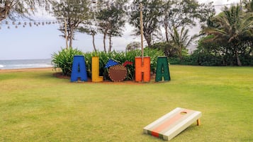 Un espacio cubierto de césped con jardineras de formas de letras de colores y una mesa para el juego de shuffleboard.