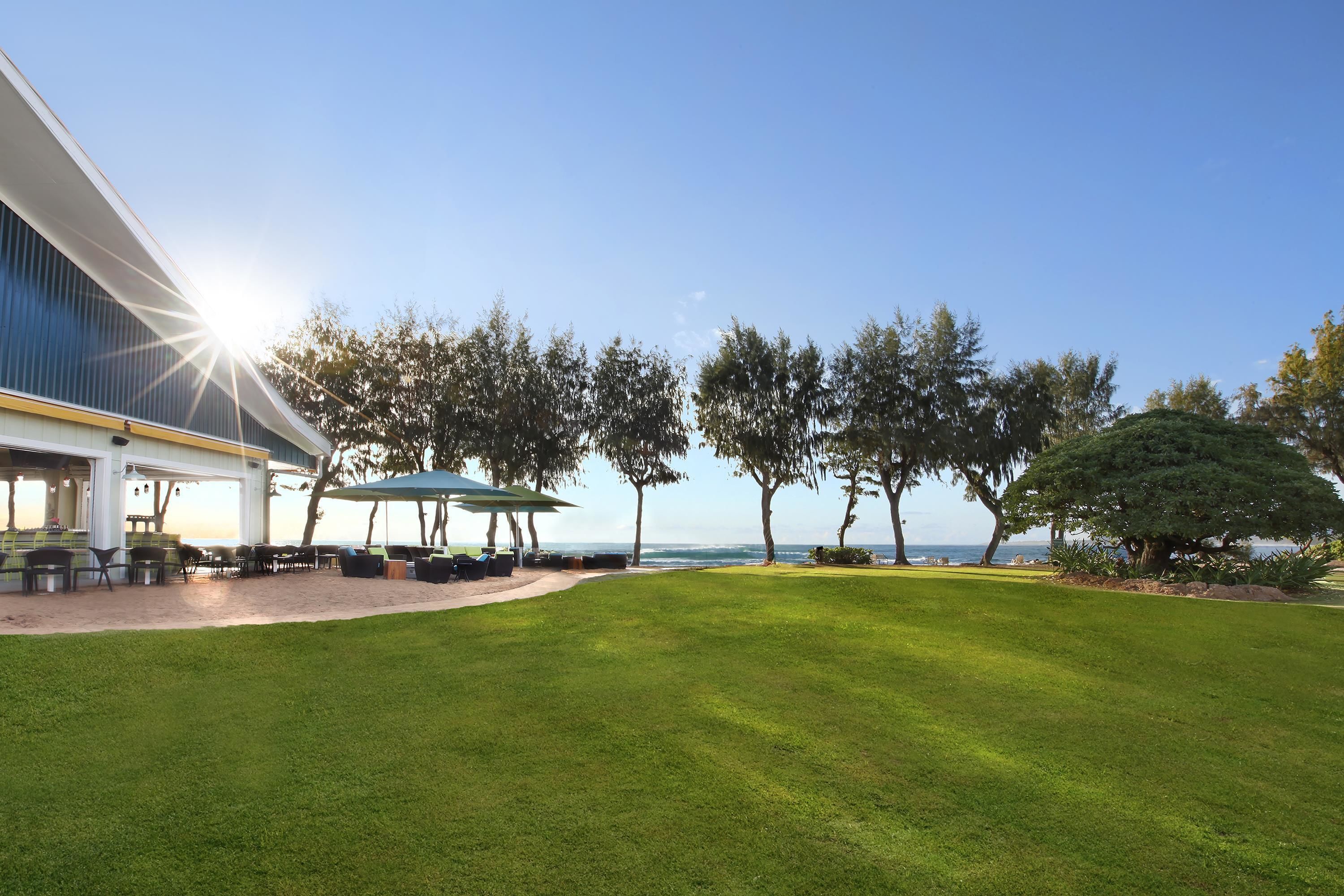 A modern building with a patio area, outdoor seating, and a view of the ocean.