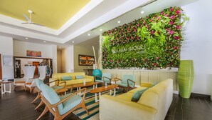 A hotel lobby with a seating area, a wall with a floral design, and a sign that reads "Kauai Shores Hotel". - Kauai Shores Hotel (Kapaa)