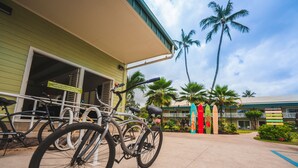 A building with bicycles parked outside, palm trees, and a signboard. - Kauai Shores Hotel (Kapaa)