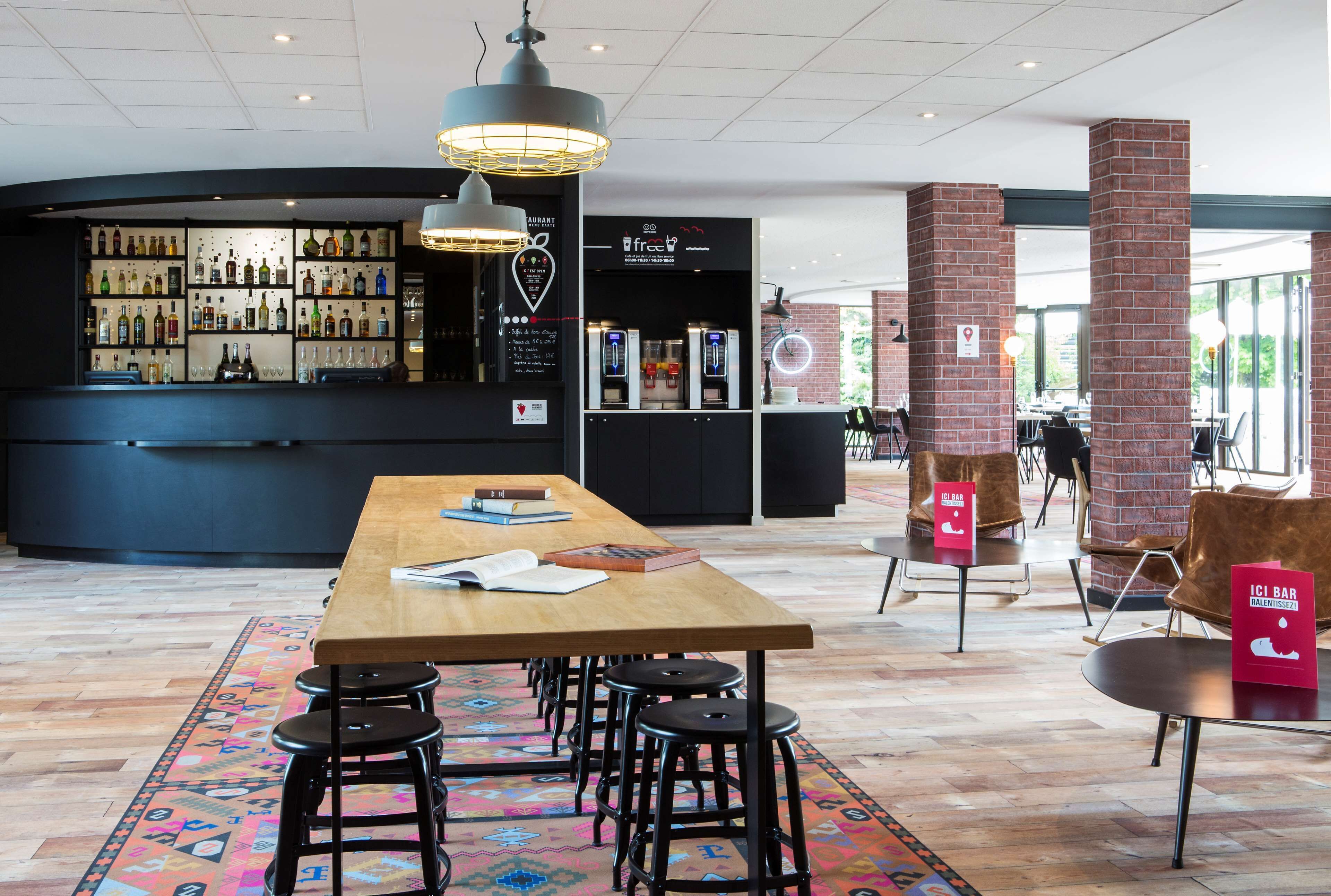 A modern bar area with a wooden table, stools, and a variety of liquor bottles.