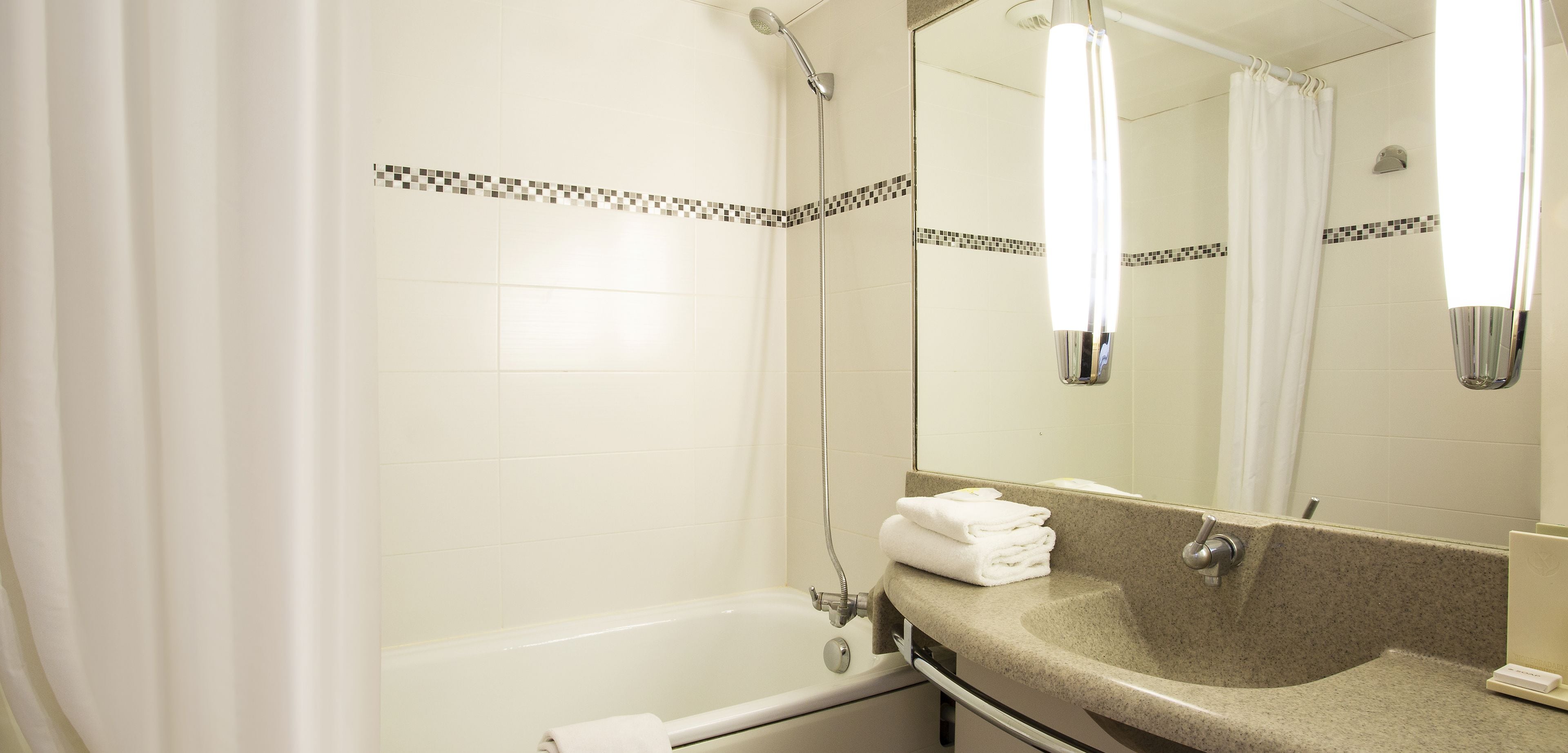 A bathroom with a bathtub, a sink, and a mirror.
