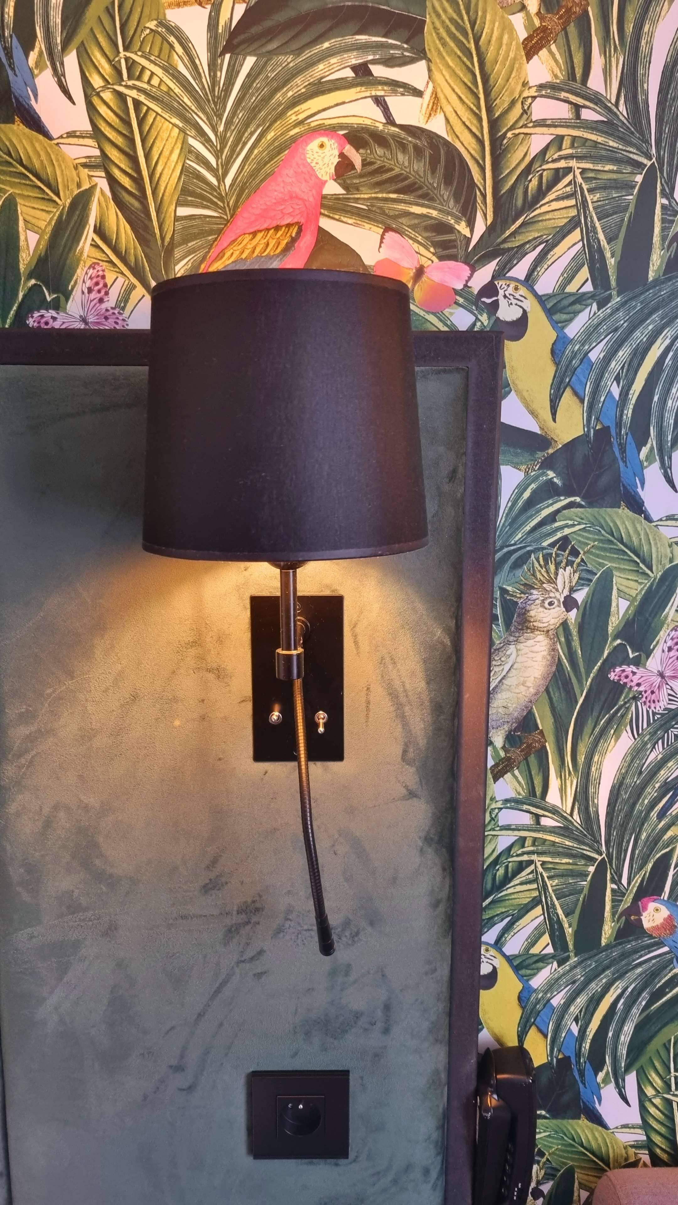Una lámpara de pared con pantalla negra, un interruptor y un enchufe.