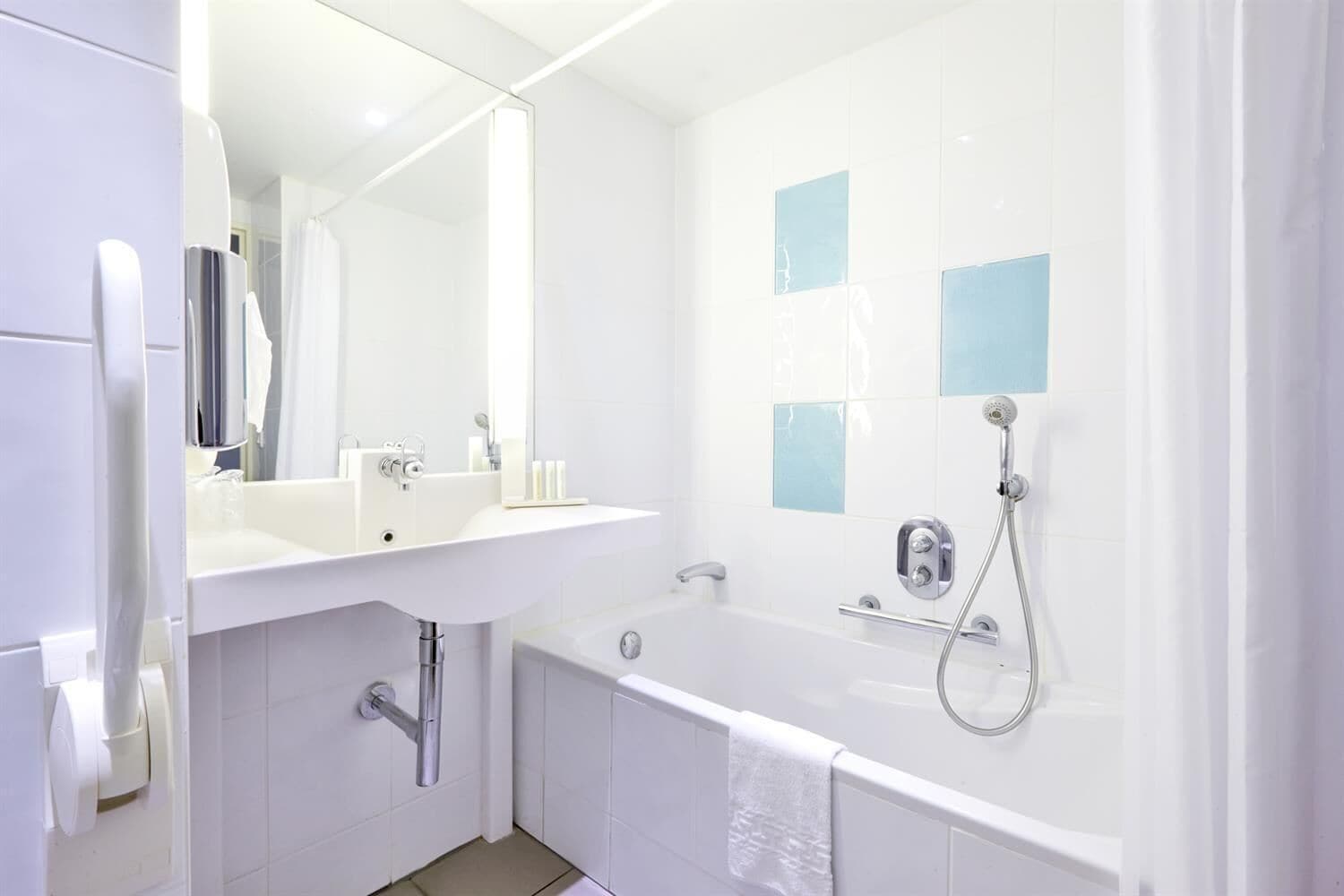 Une salle de bain moderne avec un lavabo blanc, un miroir et une baignoire.