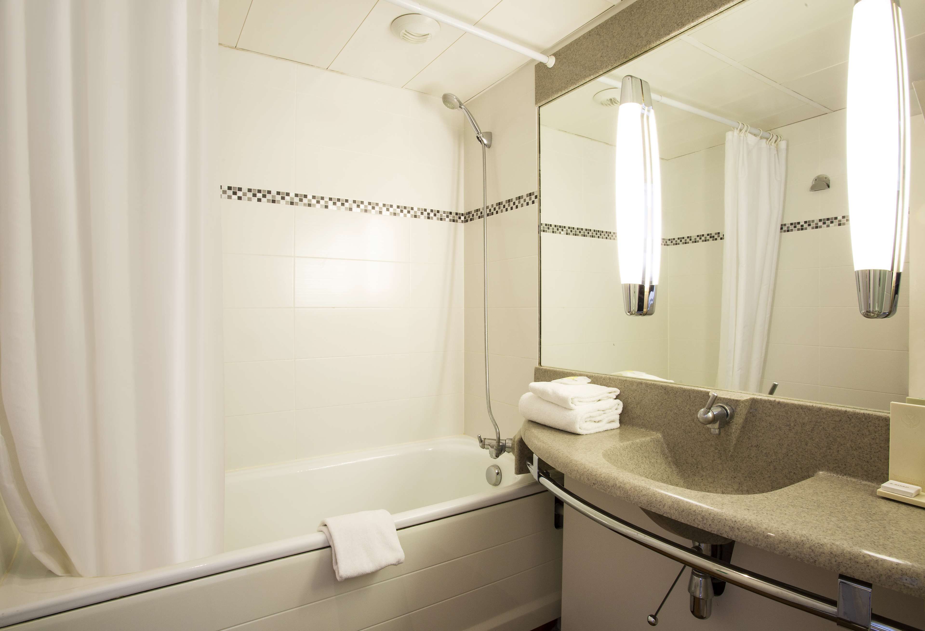 A bathroom with a bathtub, a sink, and a mirror.