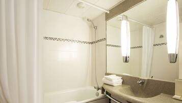 A bathroom with a bathtub, a sink, and a mirror.