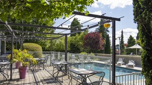 An outdoor pool area with a pergola, seating, and potted plants. - Campanile PRIME - Troyes Nord Barberey (Barberey-Saint-Sulpice)