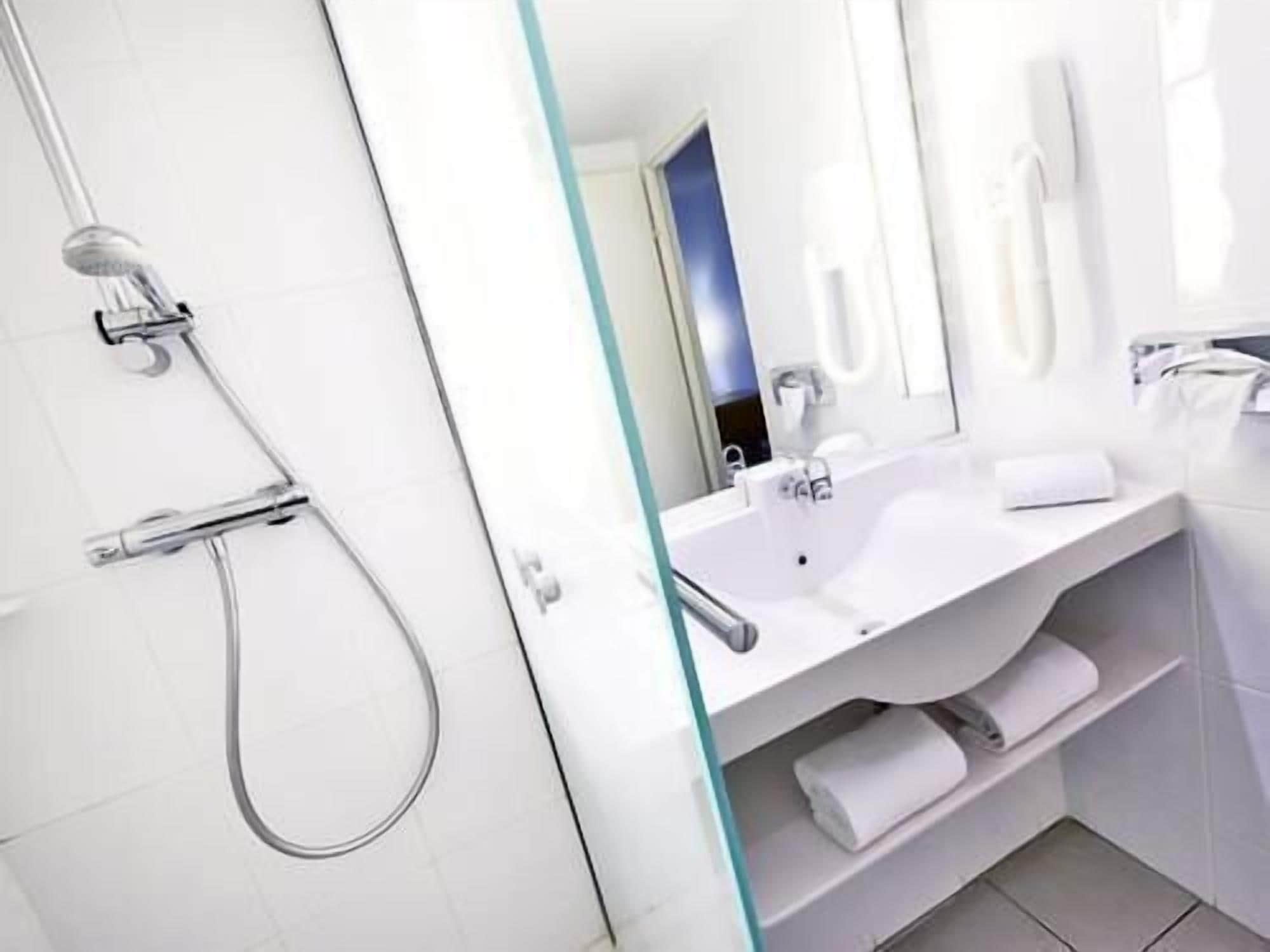 A modern bathroom with a glass shower enclosure, a white sink, and a mirror.