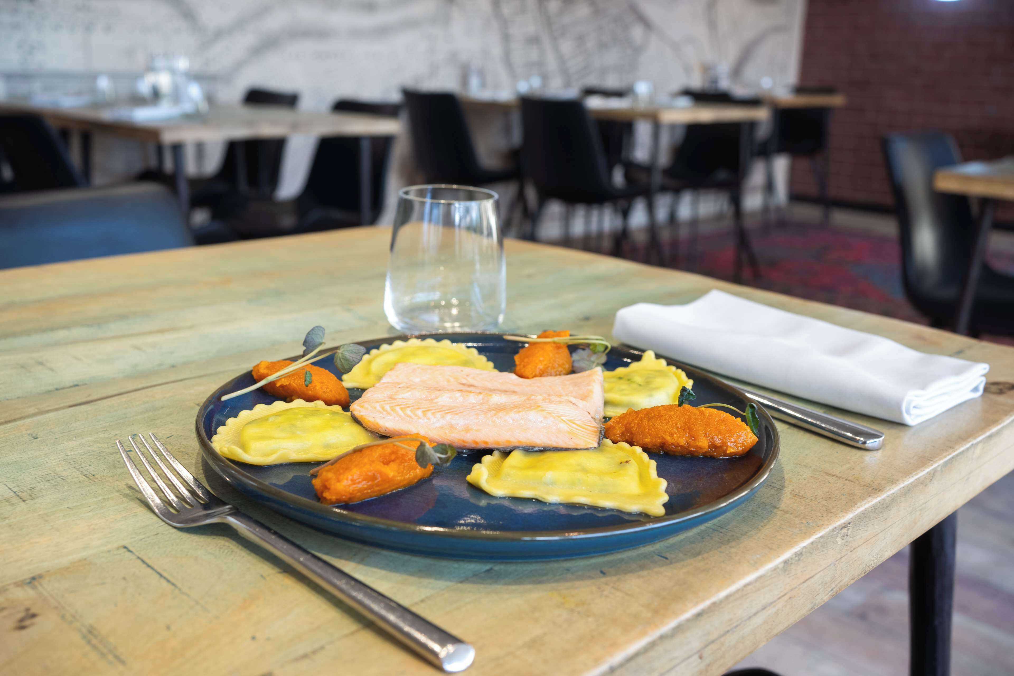 A dining table with a plate of food, a fork, a glass, and a napkin.