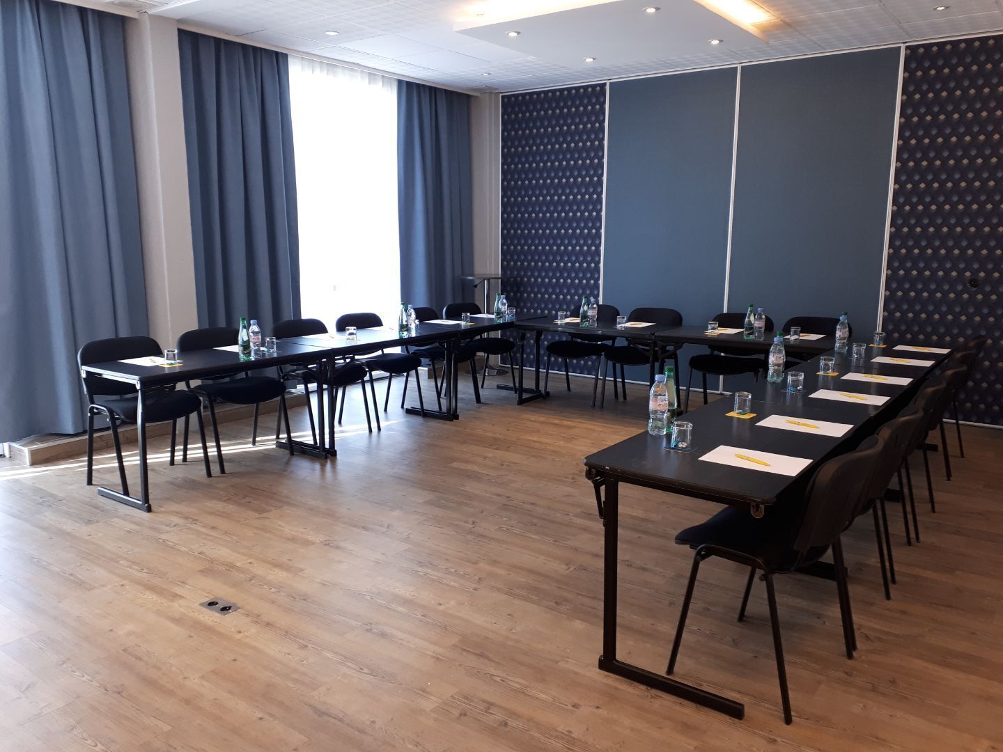 A conference room with long tables, chairs, and water bottles.