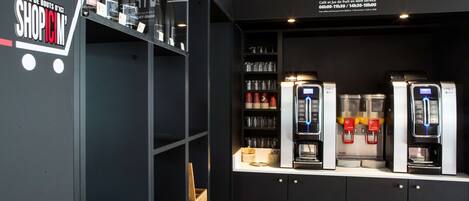 A coffee shop interior with a counter displaying coffee machines, shelves with cups and glasses, and a sign indicating free coffee service hours.