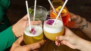 Two people holding glasses of cocktails with straws and garnishes.