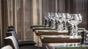 A dining area with multiple tables, each set with wine glasses, green napkins, and salt and pepper shakers.