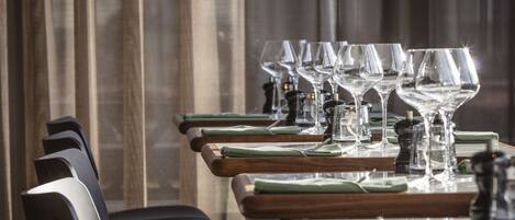 A dining area with multiple tables, each set with wine glasses, green napkins, and salt and pepper shakers.