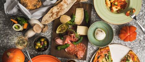A variety of food items and a pizza on a marble countertop.