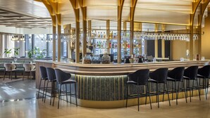 Un espace bar doté d’un comptoir incurvé, de plusieurs options d’assises et d’un intérieur bien éclairé, le tout dans un style moderne.