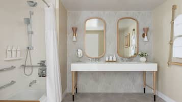 A bathroom with a shower, a bathtub, a vanity with a mirror, and a sink.