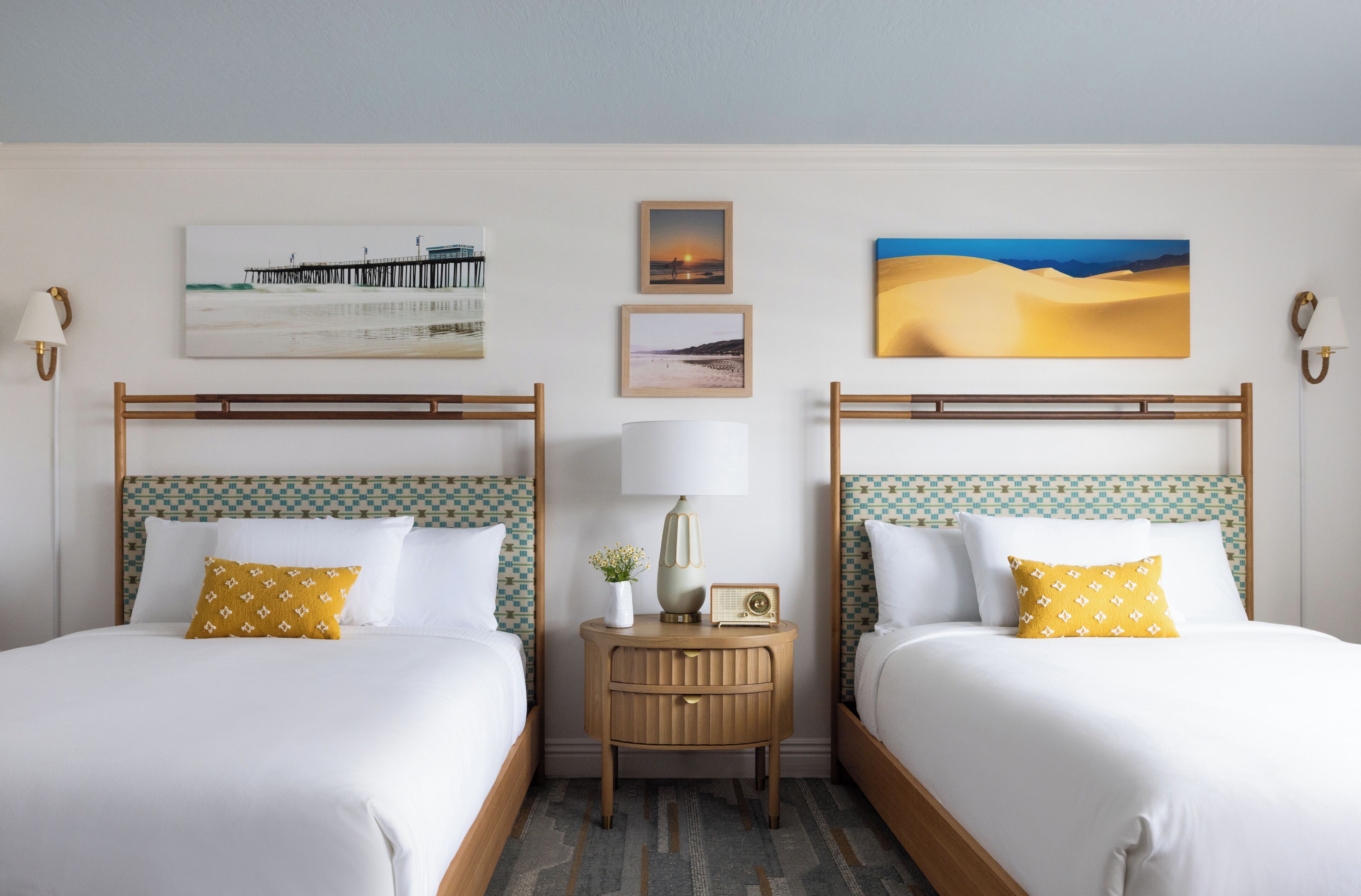 Une chambre d’hôtel avec deux lits, une table de chevet avec une lampe et des œuvres d’art murales.