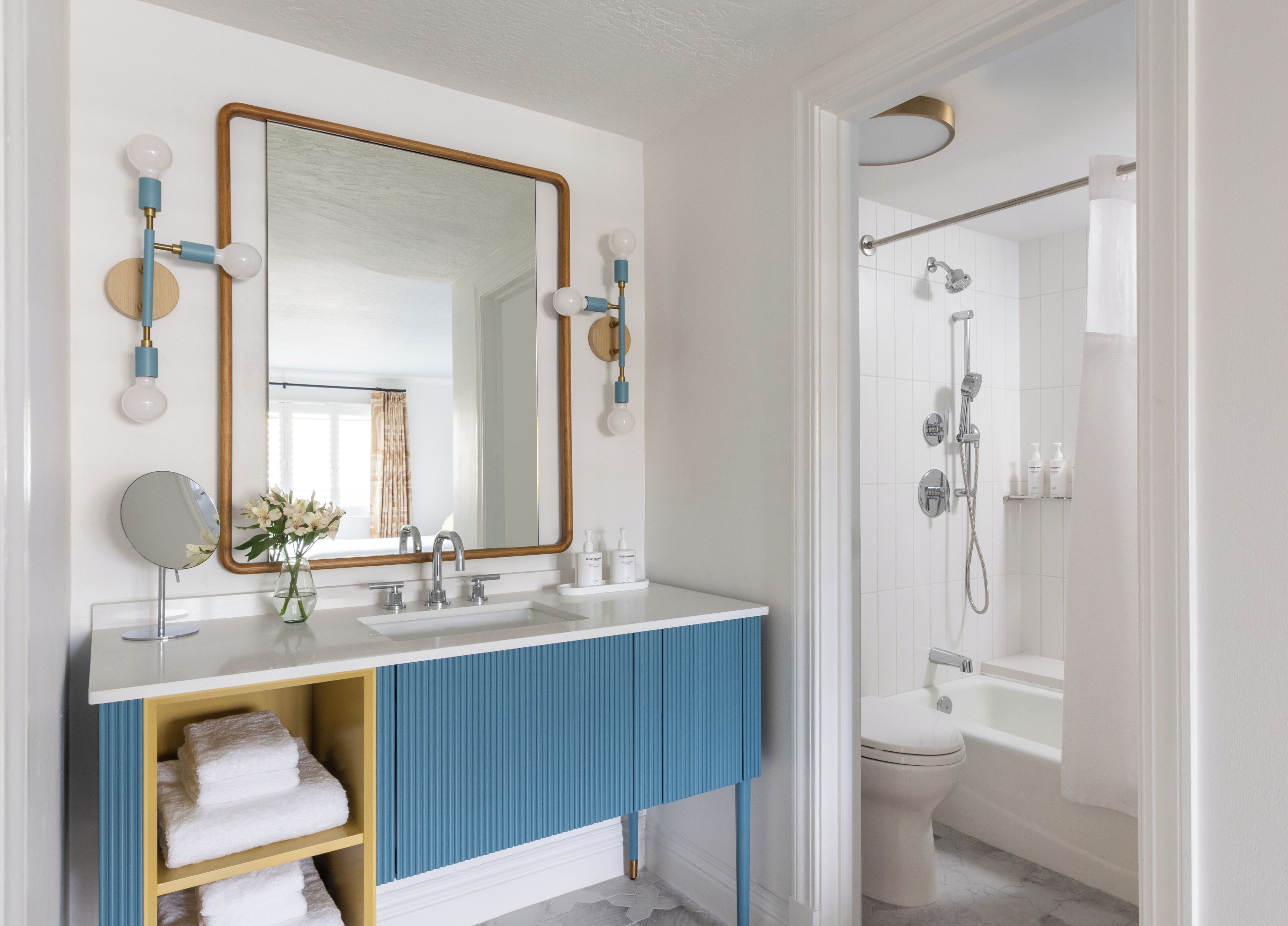 Un baño con espejo, dos lavamanos, ducha e inodoro.
