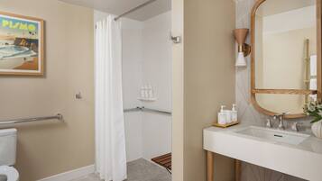 Ein Badezimmer mit Dusche, Toilette, Waschbecken und einem Spiegel mit Holzrahmen.