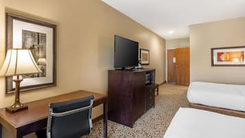 A hotel room with a bed, a desk with a lamp, a television, and a dresser.
