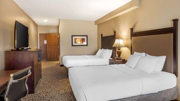 A hotel room with two beds, a desk, a television, and a framed picture on the wall.