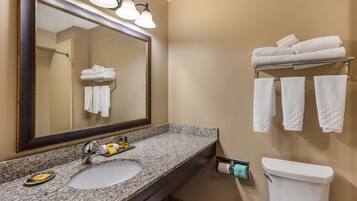 A bathroom with a granite countertop sink, a large mirror, and a towel rack with folded towels.