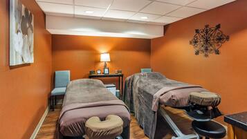 Relax in this serene space with two massage therapy beds, a table, and a lamp.