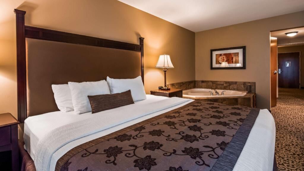 Ein Hotelzimmer mit einem großen Bett, einem Badezimmer mit Badewanne und einem gerahmten Bild an der Wand.